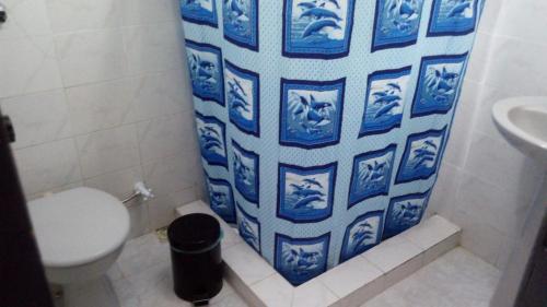 La salle de bains est pourvue de toilettes et d'un rideau de douche bleu et blanc. dans l'établissement Casa de praia S Pedro Aldeia sem TV, à São Pedro da Aldeia