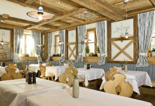 a restaurant with white tables and chairs and wooden ceilings at Ortner's Resort in Bad Füssing