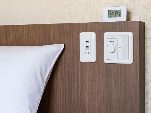 a bed with a pillow and a clock on a wall at Hotel Wing International Shimonoseki in Shimonoseki