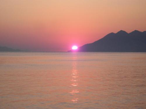 a sunset over the water with mountains in the background at Magda Hotel Apartments in Ancient Epidavros