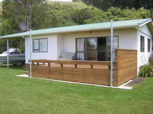 a house with a wooden deck in the yard at The Lakehouse Bach - Lake Rotoiti Bach in Rotoiti
