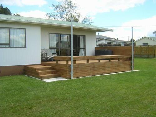 a house with a wooden deck in a yard at The Lakehouse Bach - Lake Rotoiti Bach in Rotoiti