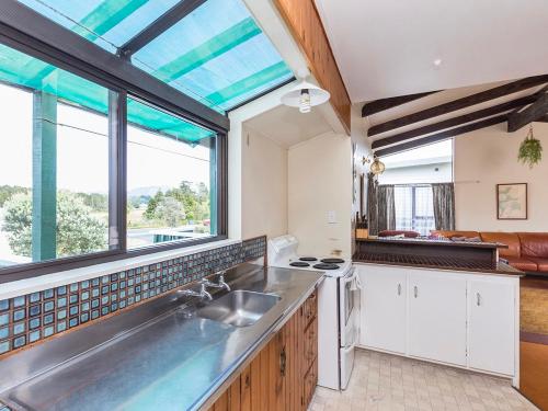 a kitchen with a sink and a large window at Kiwi Bach at Omaha - Omaha Holiday Home in Omaha