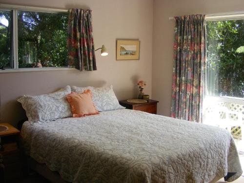 a bedroom with a bed with pillows and a window at Fernleigh - Moetapu Bay Holiday Home in Whatanihi