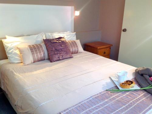 a white bed with a tray of donuts on it at El Kedira - Campbells Beach Holiday Home in Tawharanui