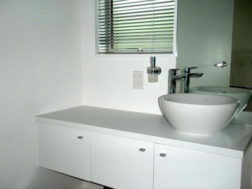 a white bathroom with a sink and a mirror at Tiromoana - Mathesons Bay Holiday Home in Leigh