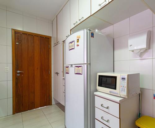 a kitchen with a white refrigerator and a microwave at MADÁ hostel in Sao Paulo
