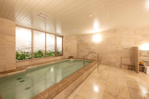 a large bathroom with a swimming pool with windows at Hotel GrandBach Sendai in Sendai
