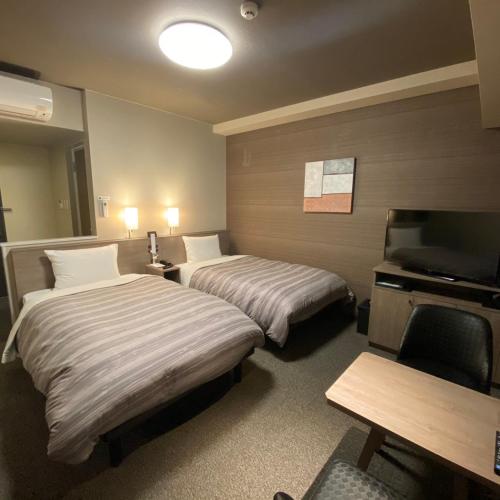 a hotel room with two beds and a television at Route Inn Grantia Tokai Spa&Relaxation in Tokai