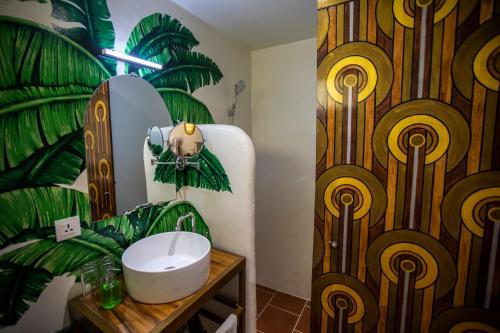 a bathroom with a sink and a palm leaf wall at Hotel Old Cinema in Kampot