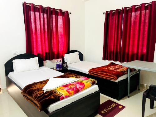two beds in a room with red curtains at Gaurav guest house in Bodh Gaya