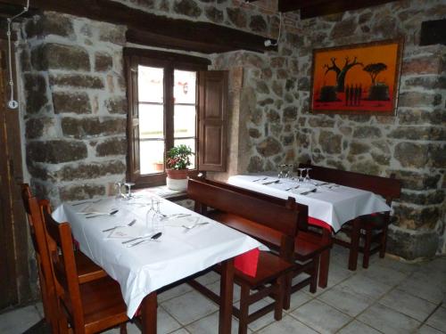 a dining room with two tables in a stone building at Hotel Rural Los Texos in La Riera