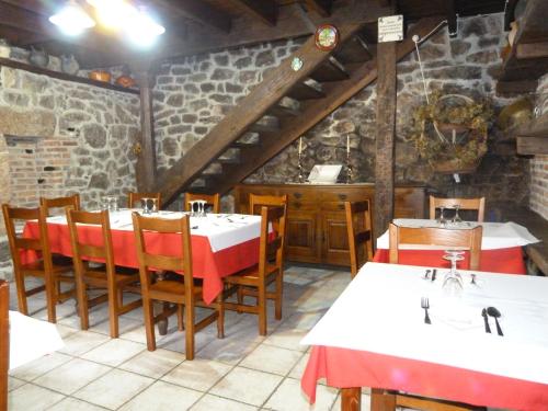 a restaurant with tables and chairs and a stone wall at Hotel Rural Los Texos in La Riera