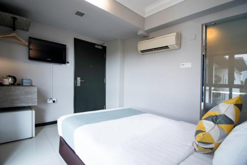 a bedroom with a white bed and a television at Harbour Ville Hotel in Singapore