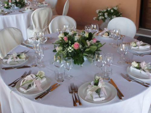 a table with white plates and a vase of flowers at La Fornasaccia in Cesena