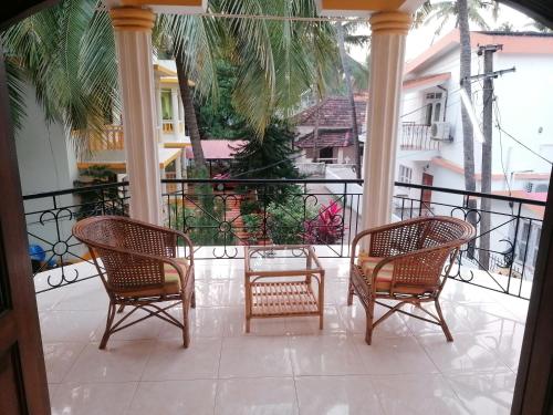 a porch with three chairs and a railing at Primavera Holiday Homes-FAMILY RUN GOAN GUEST HOUSE in Candolim