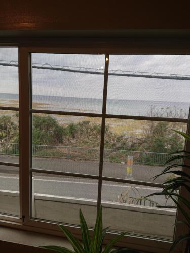 a window with a view of a road through it at Maribu Beach House in Yamada