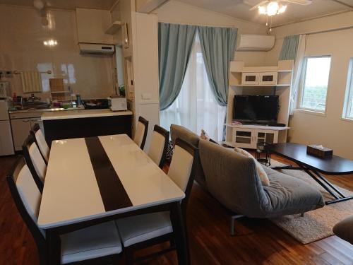 Maribu Beach House في Yamada: مطبخ وغرفة معيشة مع طاولة وكراسي