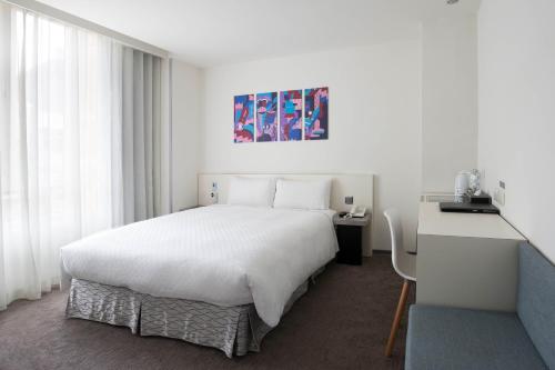 a bedroom with a large white bed and a desk at CityInn Hotel Taipei Station Branch II in Taipei