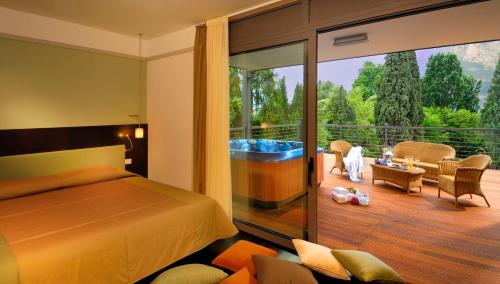 a bedroom with a bed and a balcony with a tub at Du Lac Et Du Parc Grand Resort in Riva del Garda
