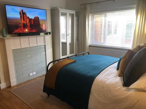 a bedroom with a bed with a tv on the wall at Herons Reach in Budleigh Salterton