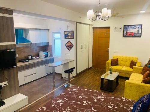 a living room with a yellow couch and a kitchen at The Karma Square near India Expo Mart in Noida