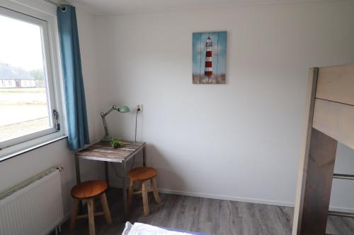 a room with a table and two stools and a window at Sier aan Zee in Hollum