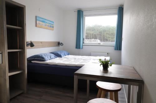 a bedroom with a bed and a table and a window at Sier aan Zee in Hollum