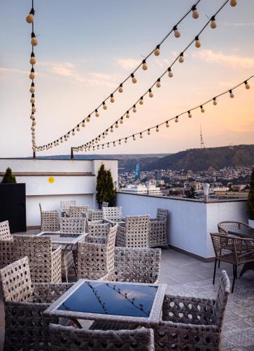 a rooftop patio with tables and chairs and lights at TM Apart Hotel in Tbilisi City