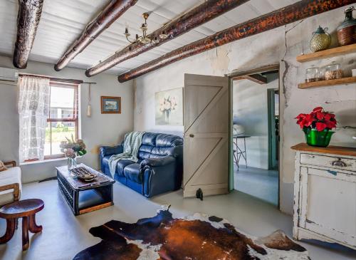 a living room with a blue couch and a door at De Kale Kat in Greyton