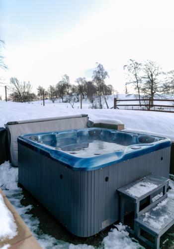 a jacuzzi tub in a snow covered yard at Pentland Lodge in Gorebridge