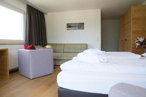a hotel room with two beds and a couch at Wellness Aparthotel Panorama Alpin - Ferienwohnungen Jerzens im Pitztal in Jerzens