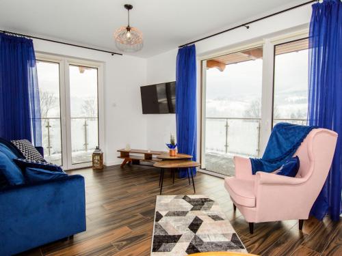 ein Wohnzimmer mit blauen Möbeln und großen Fenstern in der Unterkunft Apartamenty GÓRSKA MILA APARTZAKOP in Zakopane