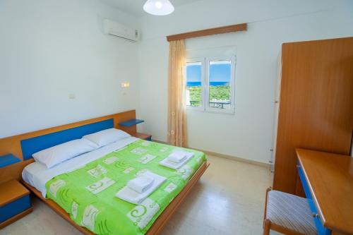 a bedroom with a bed and a desk and a window at Kavousanos Apartments in Istron