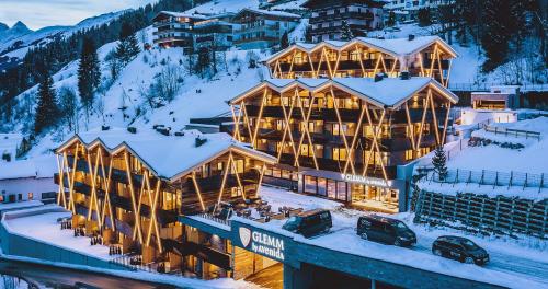 a large lodge in the snow with snow at GLEMM by AvenidA Superior Hotel & Residences in Saalbach Hinterglemm