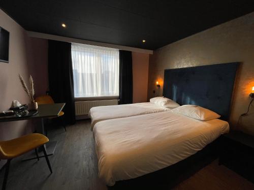 a hotel room with two beds and a desk at Hotel Restaurant Anno Nu in Oostkapelle