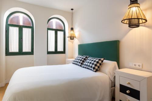 una camera con due letti bianchi e due finestre di AlohaMundi ARENAL a Siviglia