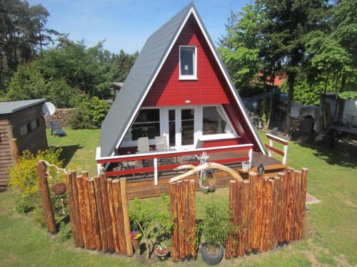 une petite maison avec un toit rouge sur une cour dans l'établissement Finnhütte Rabennest, à Freest