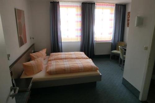 ein Hotelzimmer mit einem Bett und zwei Fenstern in der Unterkunft Hotel Eigen in Halle an der Saale