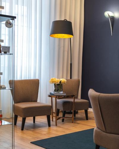 a living room with two chairs and a table with a lamp at Hotel Farol in Praia da Barra