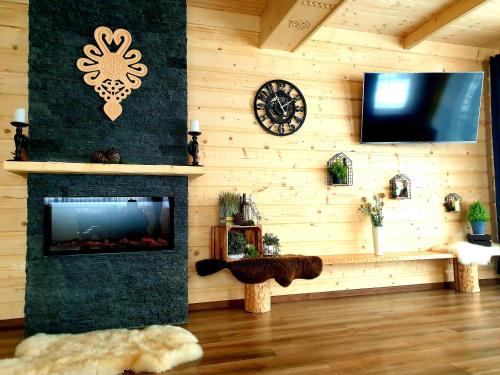 a living room with a fireplace and a clock and a tv at Domki U Hani in Murzasichle