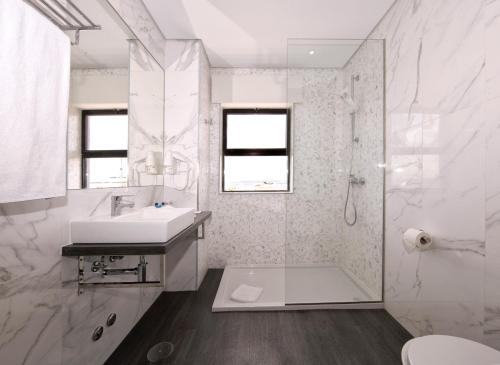 een witte badkamer met een wastafel en een douche bij Agua Hotels Alvor Jardim in Alvor