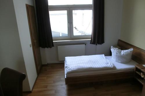 a small bedroom with a bed and a window at Hotel Schweizer Hof in Halle an der Saale