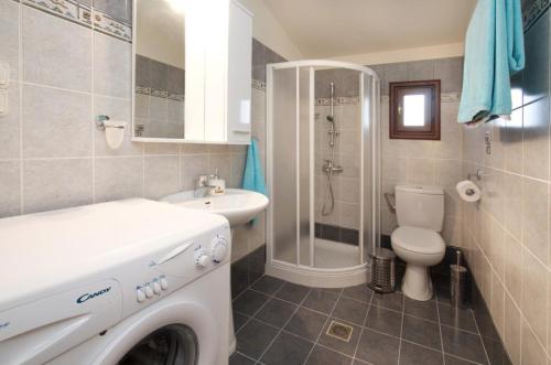 een badkamer met een wasmachine en een toilet bij Endless Blue House in Sami
