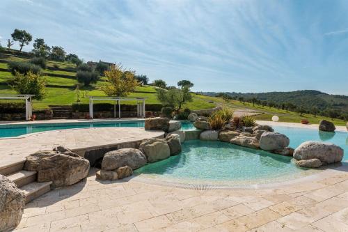 an outdoor swimming pool with rocks and a bench at Silvia in Roccalbegna