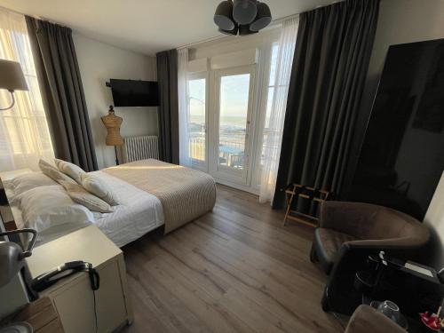 pokój hotelowy z łóżkiem i dużym oknem w obiekcie Les Fregates w mieście Veulettes-sur-Mer