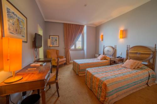 a hotel room with two beds and a desk at Hotel do Elevador in Braga