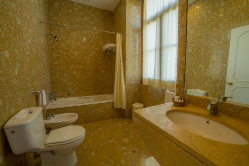 a bathroom with a toilet and a sink and a tub at Hotel do Elevador in Braga