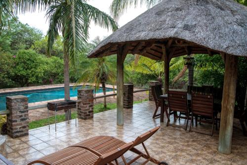 a patio with a table and chairs next to a pool at Tamboti House in Malelane