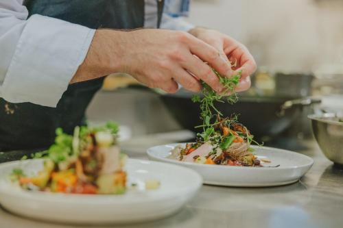 a chef preparing two plates of food on a counter at Bjäre Golfklubb Hotel & Lodge in Båstad